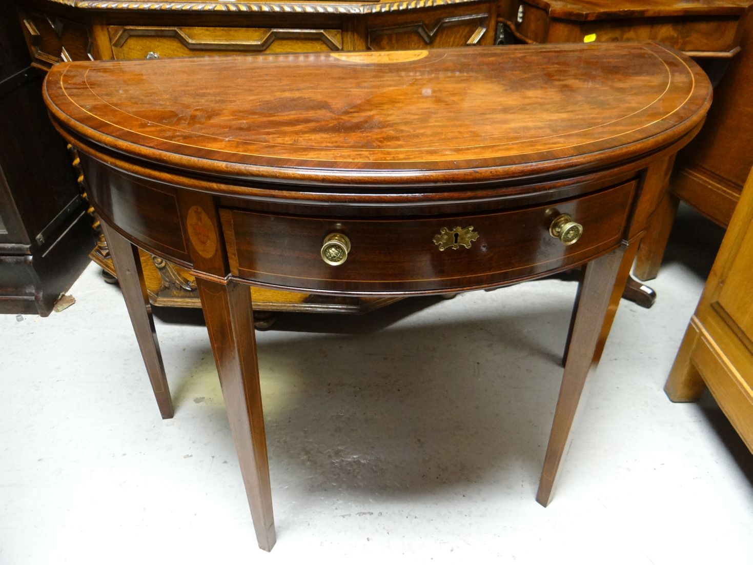 A fine quality flame-mahogany Sheraton-revival fold-over demi-lune tea-table, with inlaid shell