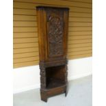 An early-twentieth century standing corner cupboard, profusely carved with figures, flowers and