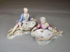 Pair of Meissen figural sweetmeat dishes in the form of a reclining man and lady on scrolling