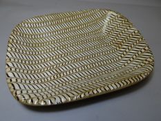 A substantial oblong cream and brown slipware dish having an all-over 'wave' pattern, 15.5 x 13