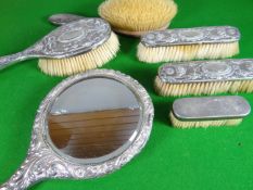 Four matching silver backed brushes, a non-matching brush and a silver backed hand mirror (parcel of
