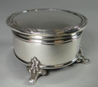 A circular silver ring-box on four floral-decorated feet and having a hinged lid with fluted and