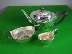 A silver three-piece oval tea-set of fluted form and with composition handle to the teapot,