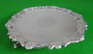 A George II silver waiter with shell and wavy border, three hoof supports and centre crest, 8.3 ozt,