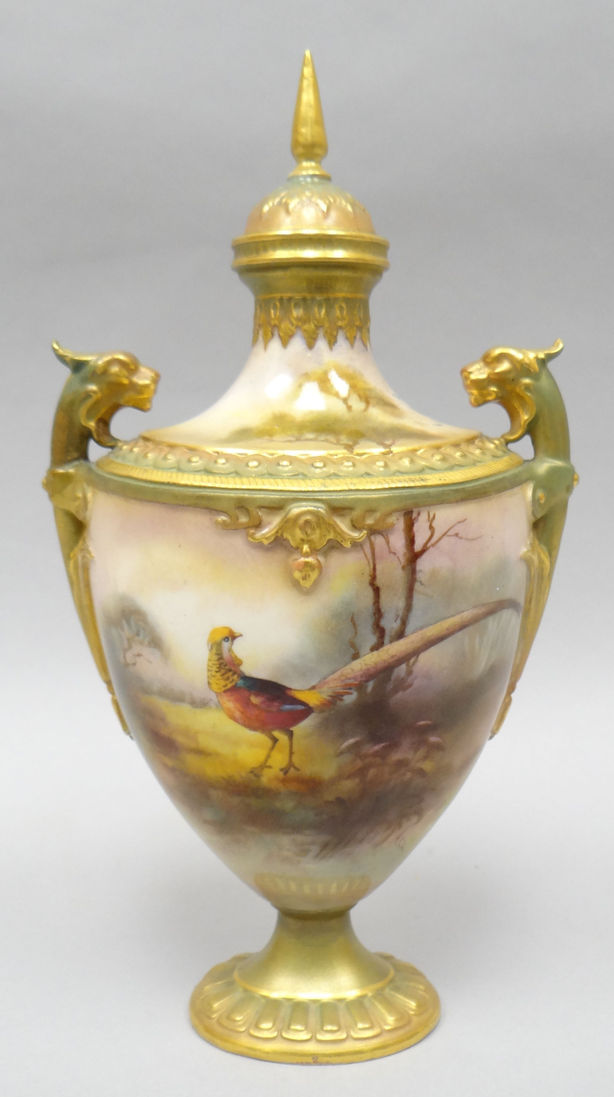 A Royal Worcester covered twin-handled vase with narrow neck on an oval base, painted all-round with