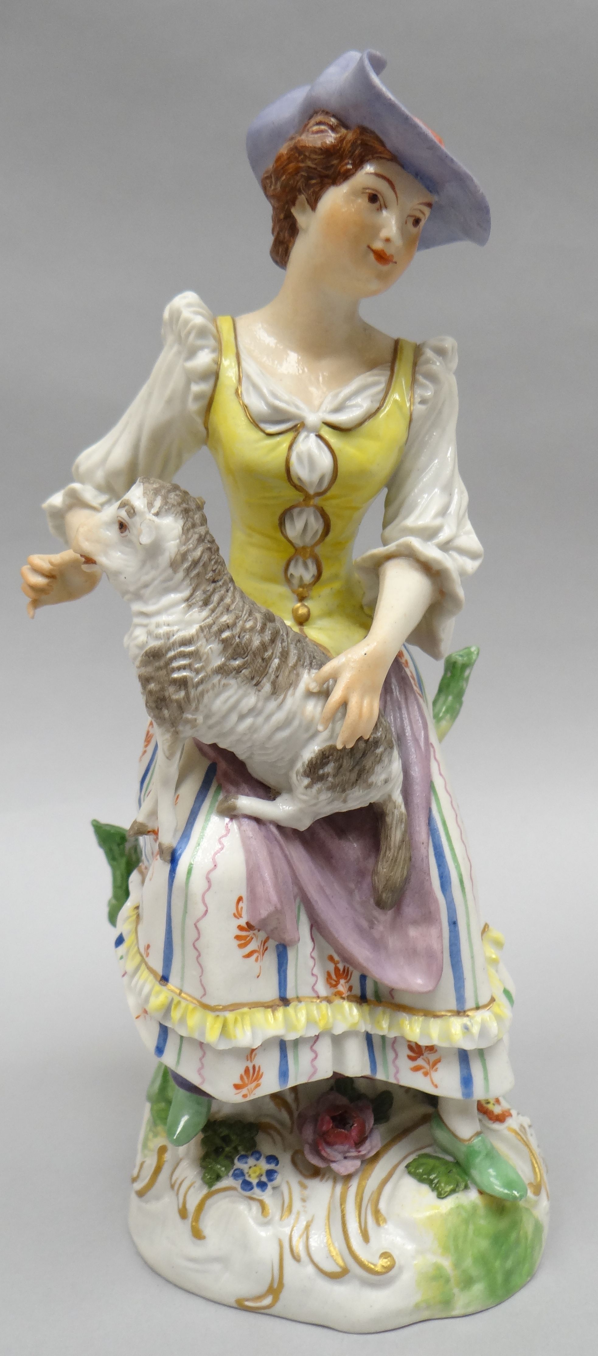 A Ludwigsburg porcelain figure modelled as a bonneted lady in colourful dress and yellow tunic,