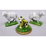 A pair of Chelsea porcelain miniature models of standing sheep on green cushion bases, gold anchor