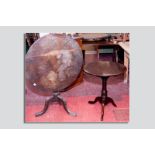 An antique mahogany tilt top tripod table having a circular top on two bearers with block mount