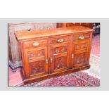 An Edwardian mahogany sideboard base having three chamfered panel doors with brass swing handles and