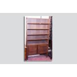 A circa 1930s oak bookcase of five open shelves with twin cupboard doors below on block supports, 72