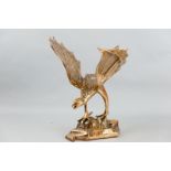 A 20th Century polished bronze sculpture of a mythical bird standing on a rocky base, its wings
