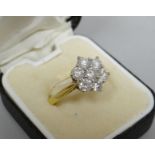 An 18kt yellow gold ring with a floral cluster of seven diamonds, cluster 1.1 cms diam