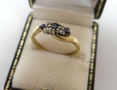 A 9ct yellow gold diamond and sapphire cross-over ring, 2.3gms