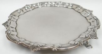 A George III shaped and footed silver salver with c-scroll and palmette rim, on four pad feet and