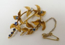 An 18ct yellow gold floral-sprig brooch set with seven sapphires and two diamonds, 6ms