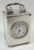 A silver encased carriage-clock of plain form with loop-handle, on bun-feet and with exposed white