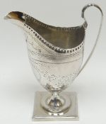 A Georgian silver square based silver helmet-shaped cream-jug with bright-cut decoration to the