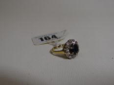 An 18ct yellow gold ring with a floral arrangement of centre dark sapphire and twelve outer small