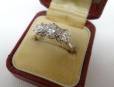 An 18ct platinum three stone diamond ring, claw set with a row of round brilliant-cut diamonds on