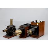 A vintage tinplate and brass Magic Lantern film projector with white pottery winder on wooden base