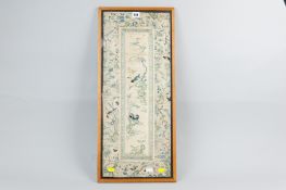 An oak framed Chinese silkwork panel decorated with birds, flowers and trees, 25 x 10 ins (63.5 x