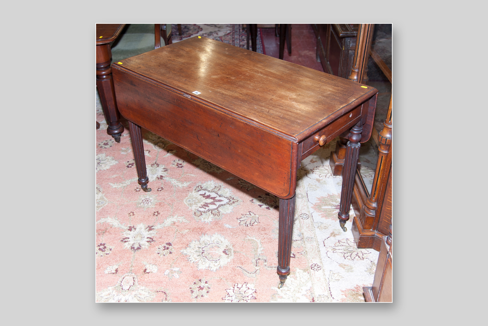 A Regency mahogany Pembroke twin flap table with single side drawer with turned knobs on reeded