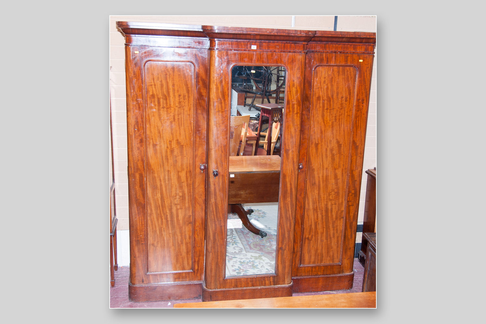 A Victorian mahogany three door breakfront wardrobe with central mirrored door, opening to reveal