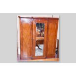 A Victorian mahogany three door breakfront wardrobe with central mirrored door, opening to reveal