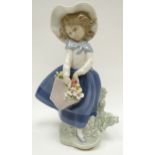 A Lladro figure of a windswept girl picking flowers for her basket, 7ins high (18cms)