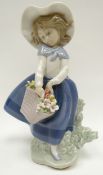 A Lladro figure of a windswept girl picking flowers for her basket, 7ins high (18cms)