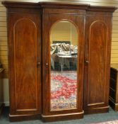 A Victorian mahogany break-front triple wardrobe with arched mirror to the centre section and