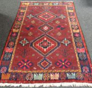 A hand-woven Iranian Yslem carpet, in ox-blood red ground  57 x 89ins (145 x 226cms)