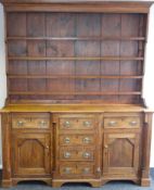 An early nineteenth century oak open-rack Welsh dresser having a break-front base with a bank of