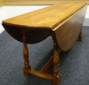 A reproduction oak plank-top 'wake' style table with drop leaves raising to an oval, 78ins long (