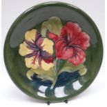 A Walter Moorcroft green-ground tube-lined floral dish, 8.75ins diam (22cms)
