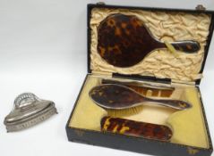 A cased four piece tortoise-shell and silver dressing-table set (damage including missing silver);