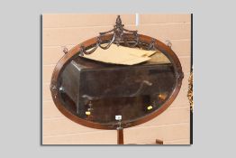 A good circa 1910 copper effect oval wall mirror with bevelled glass and central urn and swag
