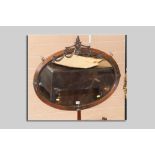 A good circa 1910 copper effect oval wall mirror with bevelled glass and central urn and swag