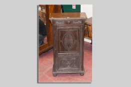 A late 19th/early 20th Century narrow carved oak cupboard having a narrow top drawer to a single