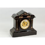 A black slate mantel clock in an architectural style case, the circular dial flanked by Corinthian