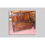 A late 18th/early 19th Century oak settle having three shaped and fielded panels to the back and