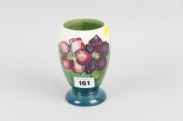A Moorcroft pottery footed vase, tube-line decorated in the clematis pattern on a cream and green