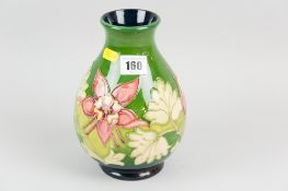 A Moorcroft pottery baluster vase decorated in the columbine pattern on a green ground, tube-lined