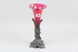 A cranberry single flute epergne on a leaf and floral relief cast metal stand, 31 cms high