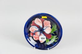 A Moorcroft pottery shallow bowl decorated in the anemone pattern on a cobalt blue ground, impressed