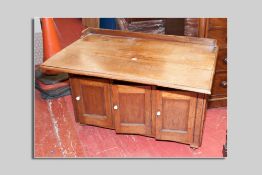 A late Victorian mahogany desk having a narrow railback, a narrow drop leaf to the front with