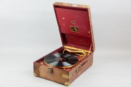 A vintage HMV wind-up picnic gramophone in a red carry case, gilt metal fittings and corner mounts