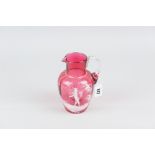 A cranberry glass jug with Mary Gregory decoration and with plain handle, 15cms high