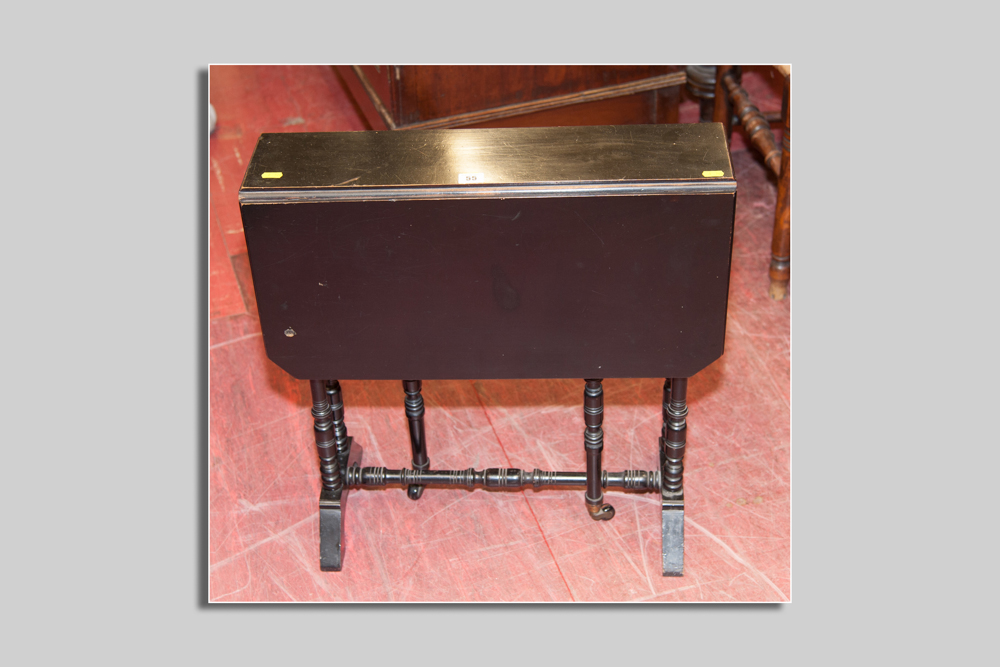 An Edwardian ebonised Sutherland table, twin flaps with canted corners, turned supports and