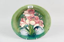 A Moorcroft pottery shallow bowl, centrally tube line decorated lily pattern in pink yellow and